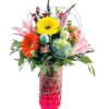 A tall, faceted magenta glass vase wrapped with a thin gold wire holds a springtime bouquet of mixed blooms and greenery. At the front, a bright orange gerbera daisy and a yellow gerbera daisy sit above a cluster of pale blue and green hydrangea petals. Pink Asiatic lilies open behind them, and a few unopened pink lily buds extend upward. Small speckled pastel eggs (light blue and pale yellow) are tucked among the foliage. A spiky blue thistle and deep red spray roses peek out toward the back, while fuzzy gray pussy willow catkins rise tall above all. Fern fronds, eucalyptus leaves, and slender green blades of grass fill in around the edges, creating a lush, textured arrangement.
