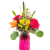A bright pink, diamond-patterned glass vase holds a colorful bouquet featuring a central yellow orchid with burgundy markings, a hot pink rose, an orange lily, small clusters of pink waxflowers, yellow billy balls, unopened lily and iris buds, and sprigs of eucalyptus and greenery.